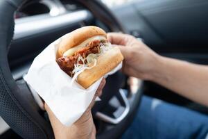 lady holding hamburger to eat in car photo