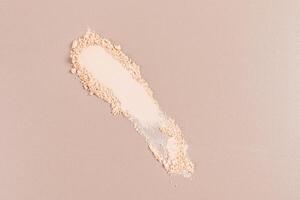 A beautiful sample texture of a dry compact powder in a natural tone on a beige background. top view. A copy space. layout product for advertising photo