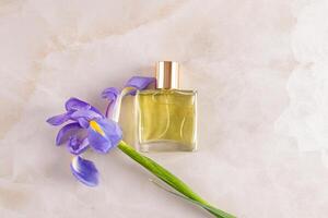 An elegant bottle of cosmetic spray or perfume with a delicate floral aroma, notes of iris on a beige background. top view. A blank bottle mockup photo