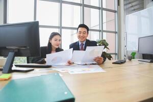 Asian man and woman discussing documents in modern office, Business people meeting in office, Team meeting and brainstorming concepts photo