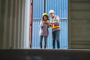 Engineer and Foreman Team in Safety Gear Inspecting Containers Box at Industrial Site, Container Yard Dock Workers Discussion at Shipping Yard photo