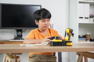 Child Learning Robotics and STEM Technology, Young Innovator Experimenting with Engineering Kit, Boy Controlling Robotic Arm at Home photo