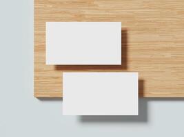 Two white business cards arranged side by side on a smooth wooden surface with a gentle shadow, emphasizing a minimalistic presentation. photo