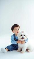 A little boy sitting on a white background with a white dog photo