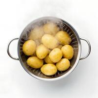 Steaming Boiled Potatoes in Metal Strainer on White photo