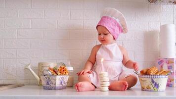 a baby in a chef hat sitting on a counter with a cake video