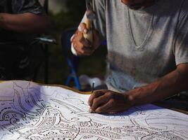 Close up hand of the craftsman is meticulously crafting traditional shadow puppets using tools and intricate techniques in a workshop. photo