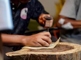 hand of the craftsman is meticulously crafting traditional shadow puppets using tools and intricate techniques in a workshop. photo
