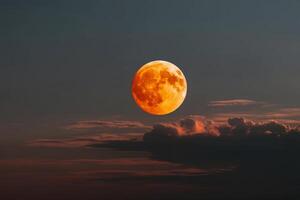 Bright orange full moon rising over dark clouds at dusk photo