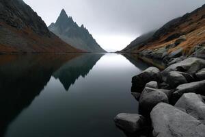 Serene mountain lake reflecting jagged peaks under cloudy sky at dawn in tranquil landscape photo