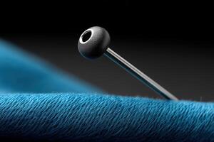Close-up view of a sewing needle threading bright blue yarn in a still life setting photo