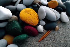Colorful collection of pebbles on a sandy beach during daytime by the shoreline photo