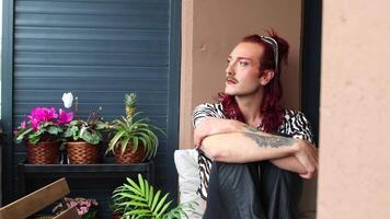 Young non-binary person relaxing on balcony with plants video