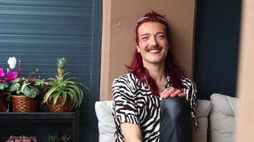 Non-binary person smiling and laughing on a balcony video