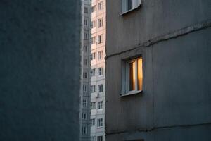 Evening light spills from a window in an urban apartment building photo