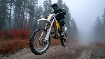 Motorcycle rider performs stunt on a dirt trail in foggy forest during late morning hours photo