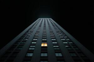 Urban night scene with glowing window in high-rise building against dark sky photo
