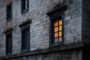 Soft glow from a window in an old stone building during twilight hours photo