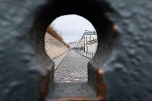 View through a keyhole of a cobblestone street in Paris on an overcast day photo
