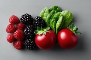 Fresh raspberries, blackberries, tomatoes, and spinach arranged on a gray background photo