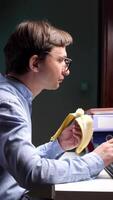 vertical close-up Office worker eating banana while working on computer at night video
