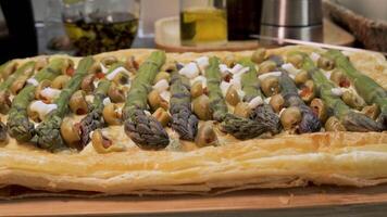 Asparagus tart with olives and cheese on puff pastry, Homemade savory tart topped with green asparagus, sliced green olives, and cheese on a crispy puff pastry base video