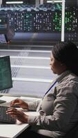 Vertical Scared technician in server room responding to hacking detection, requesting help from colleagues to protect critical data. Engineering team alerted by suspicious virus attack activity logs, camera A video
