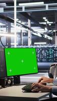 Vertical Engineer using green screen mockup PC in data center to update servers tech, configuring equipment using software tools. Server room worker reviewing hardware analytics on chroma key PC, camera A video