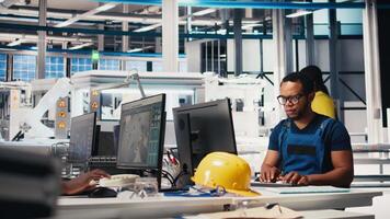 Black engineer implements automation logic in solar factory software, working on manufacturing solar panel designs for alternative energy. High tech production line. Camera B. video