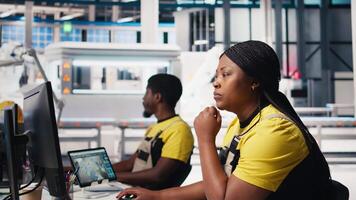 African American worker programs automation settings in solar facility, focused on efficiency and sustainability. Female engineer manages configurations for improved power output. Camera B. video