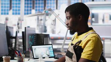 PC based solar technician reviews automation data in production factory, manufacturing industry focused on renewable energy. Worker tracks solar panels and machine performance. Camera A. video