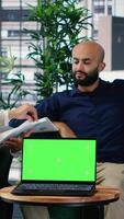 Vertical Business people negotiate to align on vision next to mockup display on laptop, using data driven insights and cultural diversity to support leadership and corporate success. Camera B. video