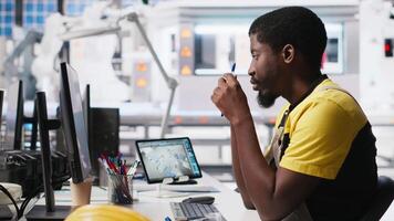 African american technician evaluates renewable energy metrics at pc station, using advanced monitoring and manufacturing tools. Engineer improves solar power system accuracy. Camera A. video