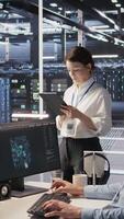 Vertical Data center team of technicians working on neural network software development. Server hub colleagues implementing deep learning artificial intelligence technology in workplace, camera A video