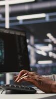 Vertical Close up of data center admin coding, writing script on PC identifying bottlenecks. Server farm IT expert typing on computer keyboard, troubleshooting bugs, implementing optimizations, camera A video