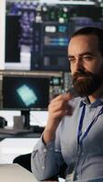 Vertical Data center technician discussing with coworker while doing AI software updates. Server room IT specialist and colleague chatting, optimizing infrastructure using artificial intelligence, camera A video