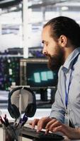 Vertical Panicked engineers in data center react to ransomware warning on PC display, scrambling to launch emergency response protocol. IT staff urgently trying to fix hacked infrastructure systems, camera A video