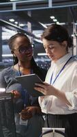 Vertical Teamworking engineers in data center integrate AI automation tools together during maintenance session. Server room colleagues configure machine learning models across server infrastructure, camera A video