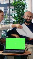Vertical CEO and executive team conducting research next to green screen in a corporate environment, developing strategy and sharing expertise to drive company investment and performance. Camera A. video