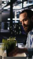 Vertical Furious data center engineer packs desk belongings after being replaced by AI automation handling operations. Frustrated man suffering from workforce displacement by artificial intelligence, camera A video