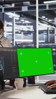 Vertical Data center admin using isolated screen PC to monitor neural network AI. Server room employee using mockup computer to oversee rigs powering machine learning processes, camera A video