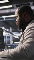 Vertical Data center computer scientist monitoring servers performing AI training and inference tasks. African american server hub worker overseeing computing systems managing deep learning storage, camera A video
