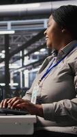 Vertical Data center computer scientist using PC to monitor artificial intelligence visualization. Server farm IT professional overseeing rigs powering machine learning processes, camera A video