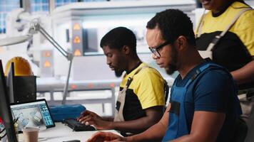 Team of black technicians works on PC setups in solar energy facility, using advanced industrial software. Colleagues troubleshooting solar panel systems for automated assembly. Camera A. video