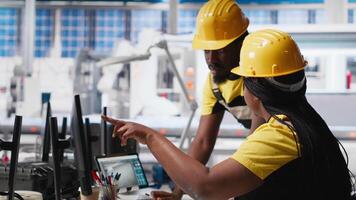 All black team of engineers comparing solar panels designs on devices, working on the production line at the manufacturing plant. Troubleshooting together and ensuring optimization. Camera A. video