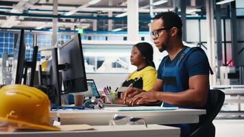 Engineer monitors solar power output in high tech production facility at a desk inside a solar factory. Specialist analyzes data to improve energy efficiency and equipment performance. Camera B. video