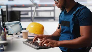 African american engineer manages data from solar machinery on desktop, working in a solar panel manufacturing factory. Male technician in automated renewable energy production line. Camera A. video