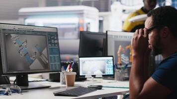 African american wheelchair user working in solar panel factory, optimizing systems for renewable energy. Engineer examines robot arms automation in a disability friendly power plant. Camera A. video