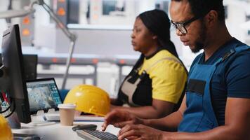 Employee uses computer to control robotic arms in solar factory in a high tech sustainable facility. Technician adjusts automation settings to support consistent manufacturing. Camera A. video