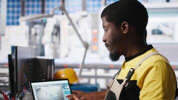 Black engineer develops power optimization models in solar panel production, working on PC software to increase renewable energy photovoltaic systems. Eco friendly industry. Camera A. video